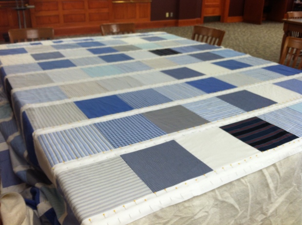 Blue and white quilt being sandwiched on tables