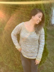 Image of Tina Tse wearing her Golden Horizon Sweater in a garden as sun flashes across the camera lens, image copyright Tina Tse
